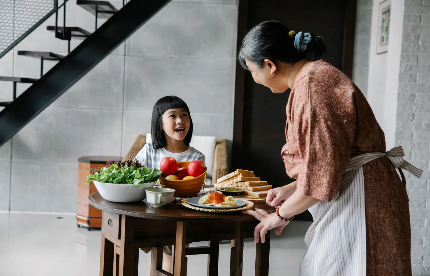 A grandmother serving a healthy breakfast to her granddaughter at home