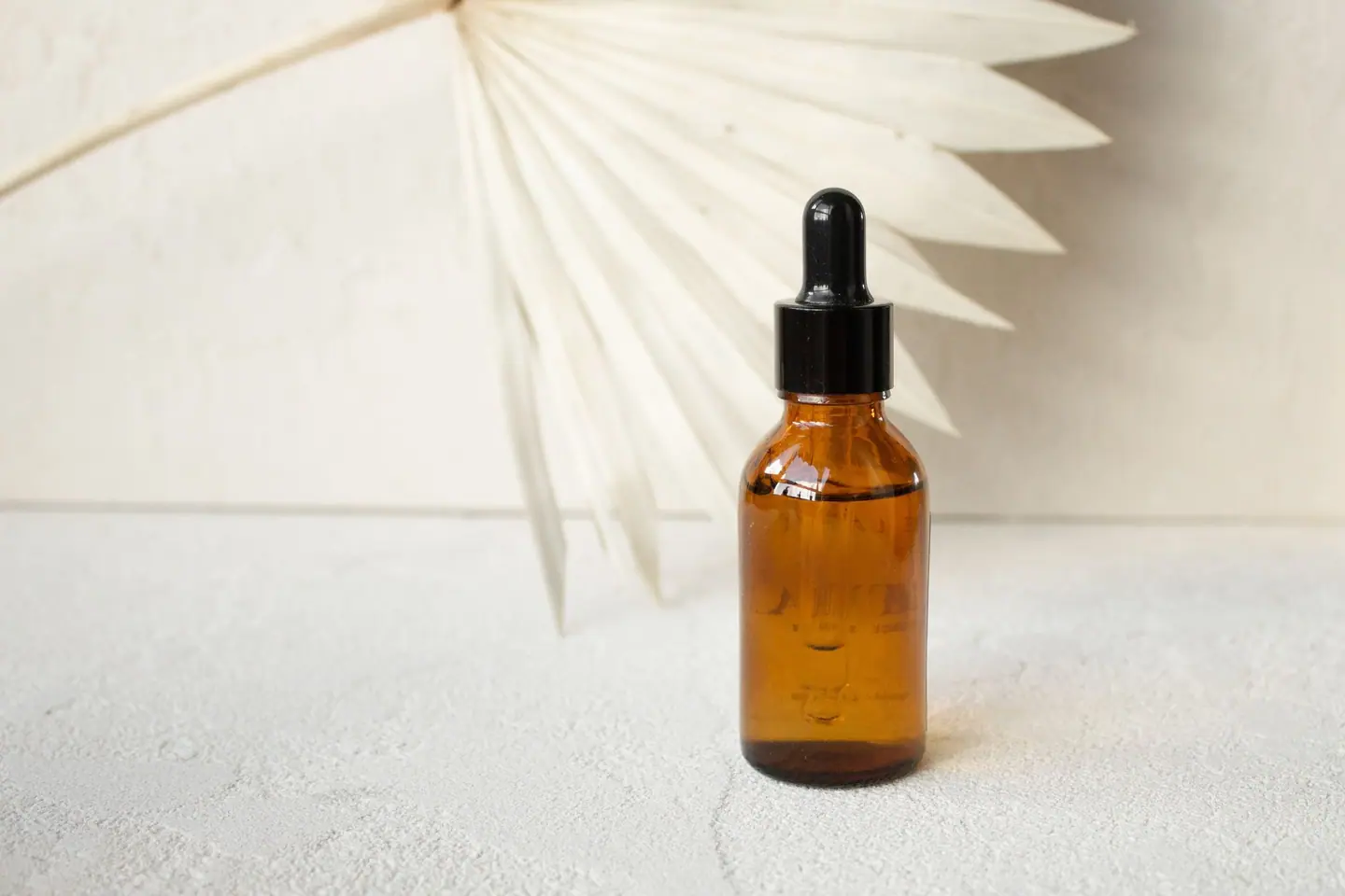 An amber glass dropper bottle on a light stone surface