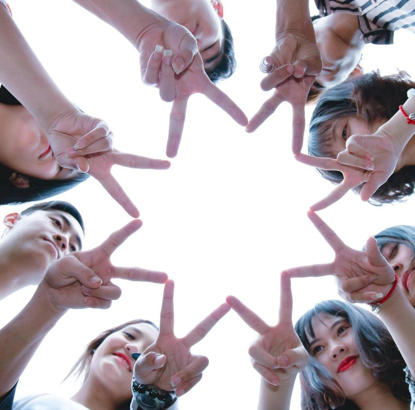 A group of friends seen from below, their hands joined in a star